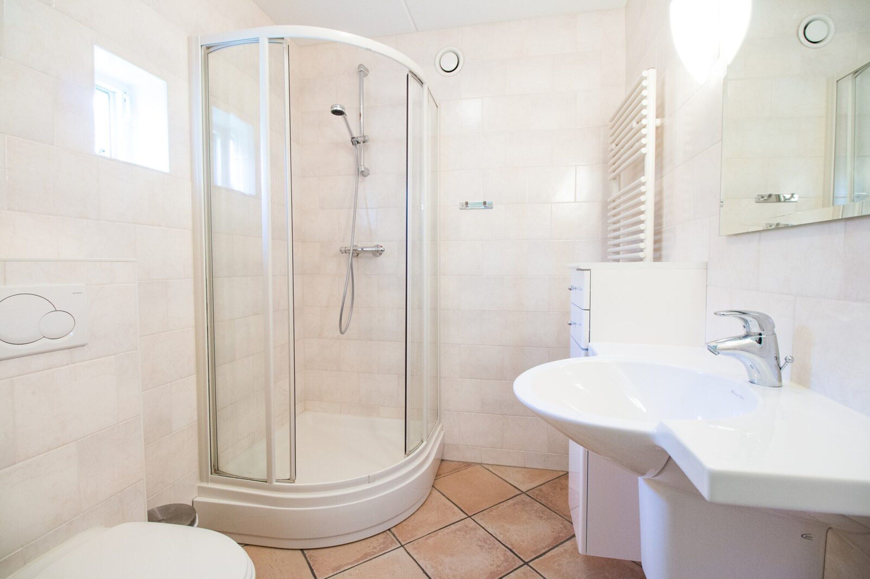 A modern bathroom with a glass-enclosed shower, a white sink, and a toilet.