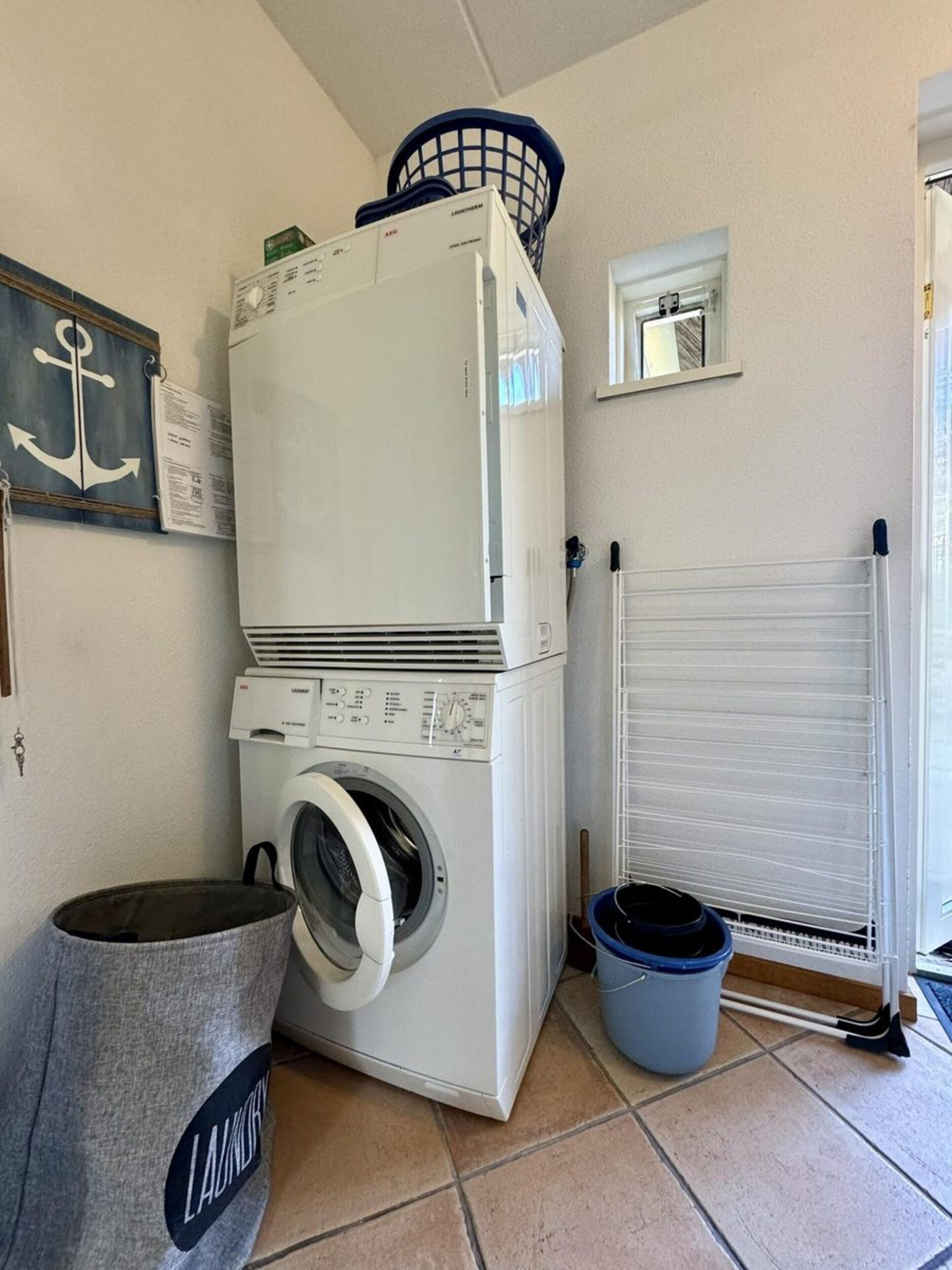 A laundry room with stacked appliances, a bucket, and a keychain.