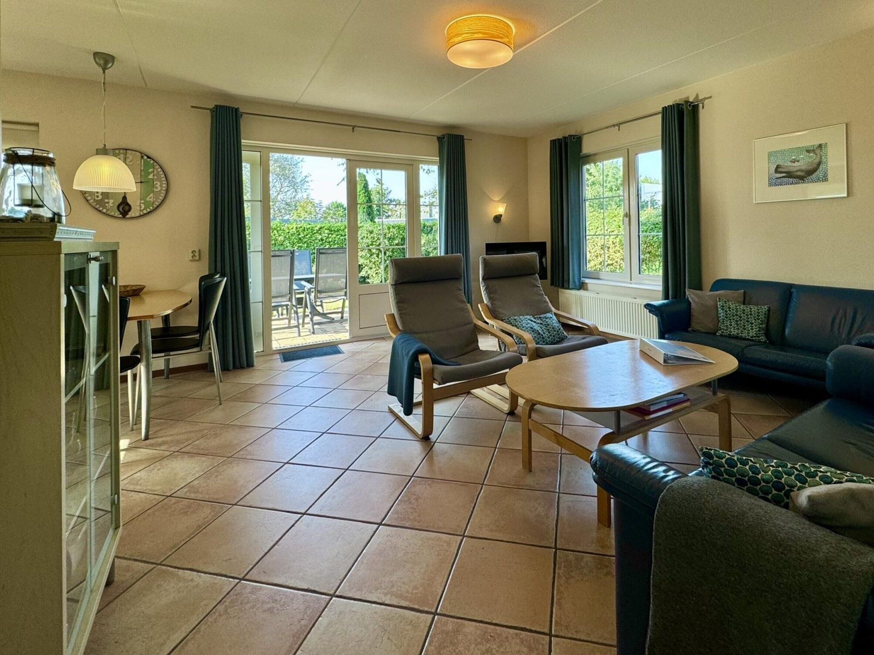 A spacious living room with a sofa, two armchairs, a coffee table, and a dining area with chairs and a table.