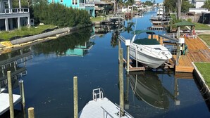 Een jachthaven met aangemeerde boten, een houten steiger en een huis met een blauw dak.
