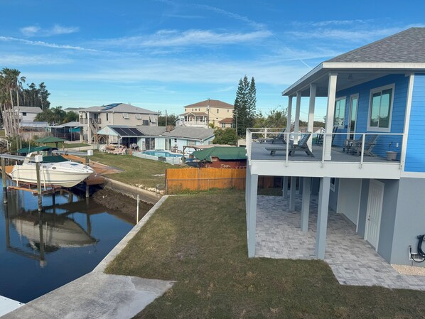 Una propiedad residencial con piscina, un barco amarrado al borde del agua y un área de patio cubierta.