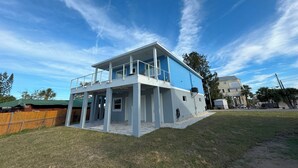 Een huis met twee verdiepingen, een balkon, een overdekte veranda en een omheinde tuin.