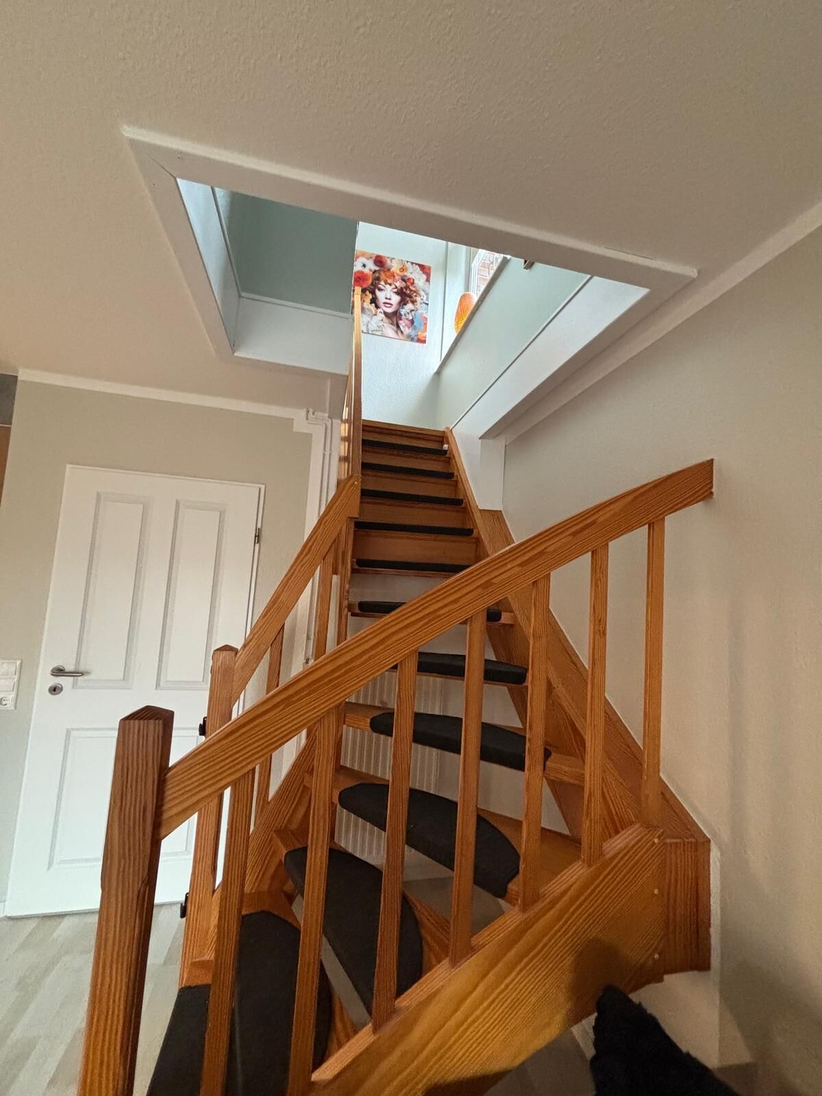 A wooden staircase with a skylight leading to a room.