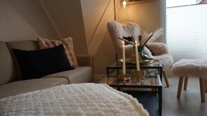 A cozy room with a sofa, a glass coffee table with candles, and a fluffy chair. - Fewo Schill und Mee(h)r, modern apartment in the center, pets allowed. (Wangerland)