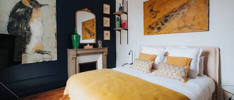 Un dormitorio con una cama grande, una chimenea y obras de arte en las paredes.