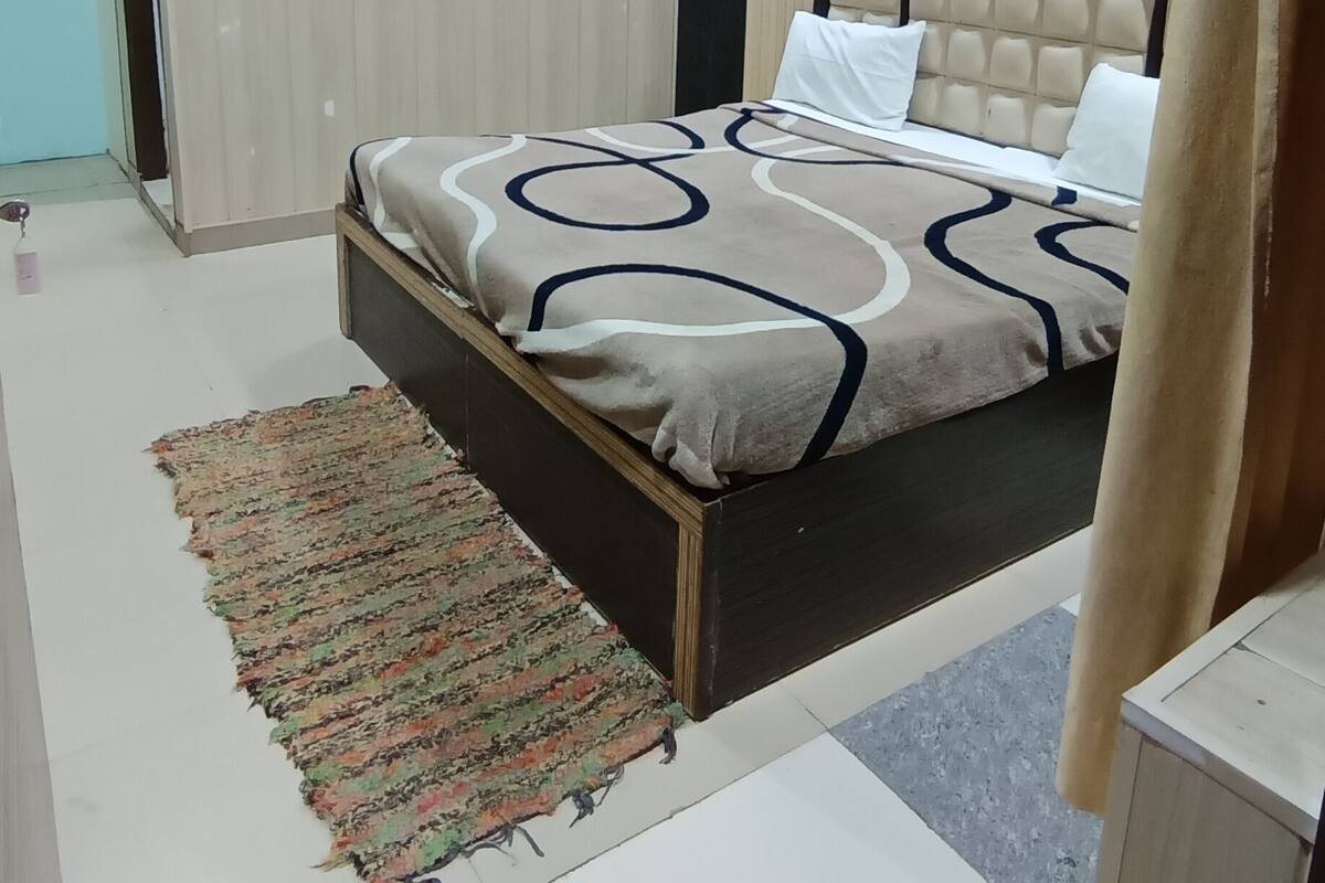 Un dormitorio con cama, ventilador de techo, equipo de aire acondicionado y alfombra estampada.