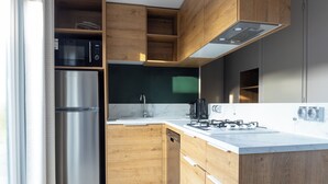 A modern kitchen with wooden cabinets, a stainless steel refrigerator, a built-in dishwasher, a gas stove, and a black microwave.