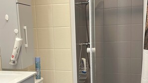 Une salle de bain moderne comprenant des toilettes, un espace douche et un lavabo avec un miroir.