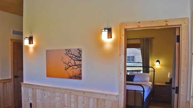 A bedroom with a bed, bedside table, and wall-mounted light fixtures. - Johnson's Shut-ins State Park (Middle Brook)