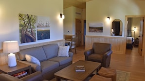 A cozy living room with a sofa, armchairs, a coffee table, and a lamp. There are wall art pieces and a mirror. - Johnson's Shut-ins State Park (Middle Brook)