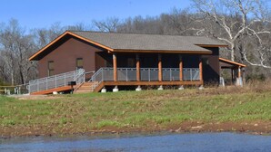 A cabin with a porch and steps leading to a deck, situated near a body of water. - Johnson's Shut-ins State Park (Middle Brook)