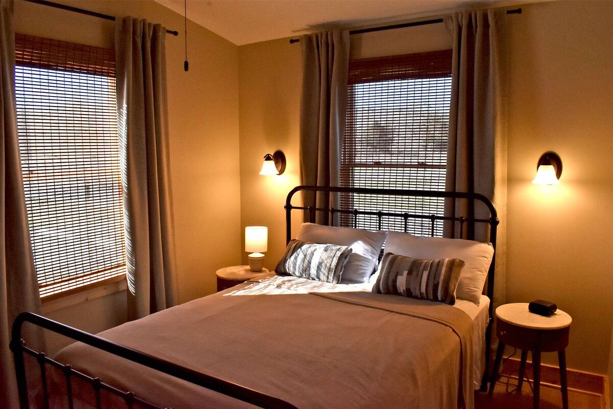 Une chambre à coucher comprenant un lit, deux tables de chevet et deux lampes fixées au mur.