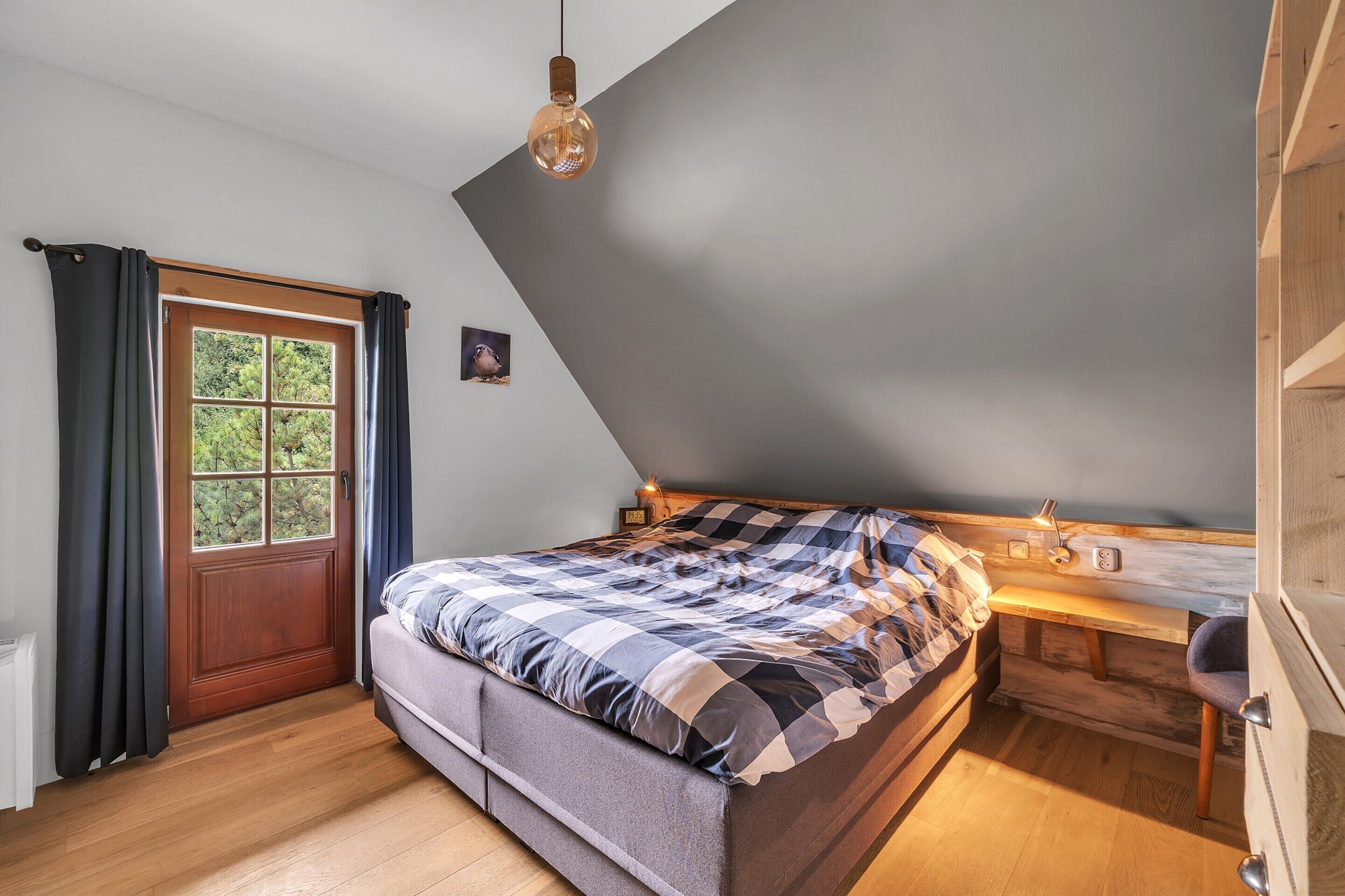 Un dormitorio con una cama, un escritorio y una ventana con cortinas.