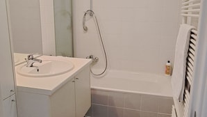 Moderni kylpyhuone, jossa on valkoinen pesuallas, peili ja kylpyamme.
