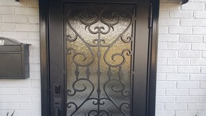 En svart dörr med detaljerat metallarbete och en glasruta.
