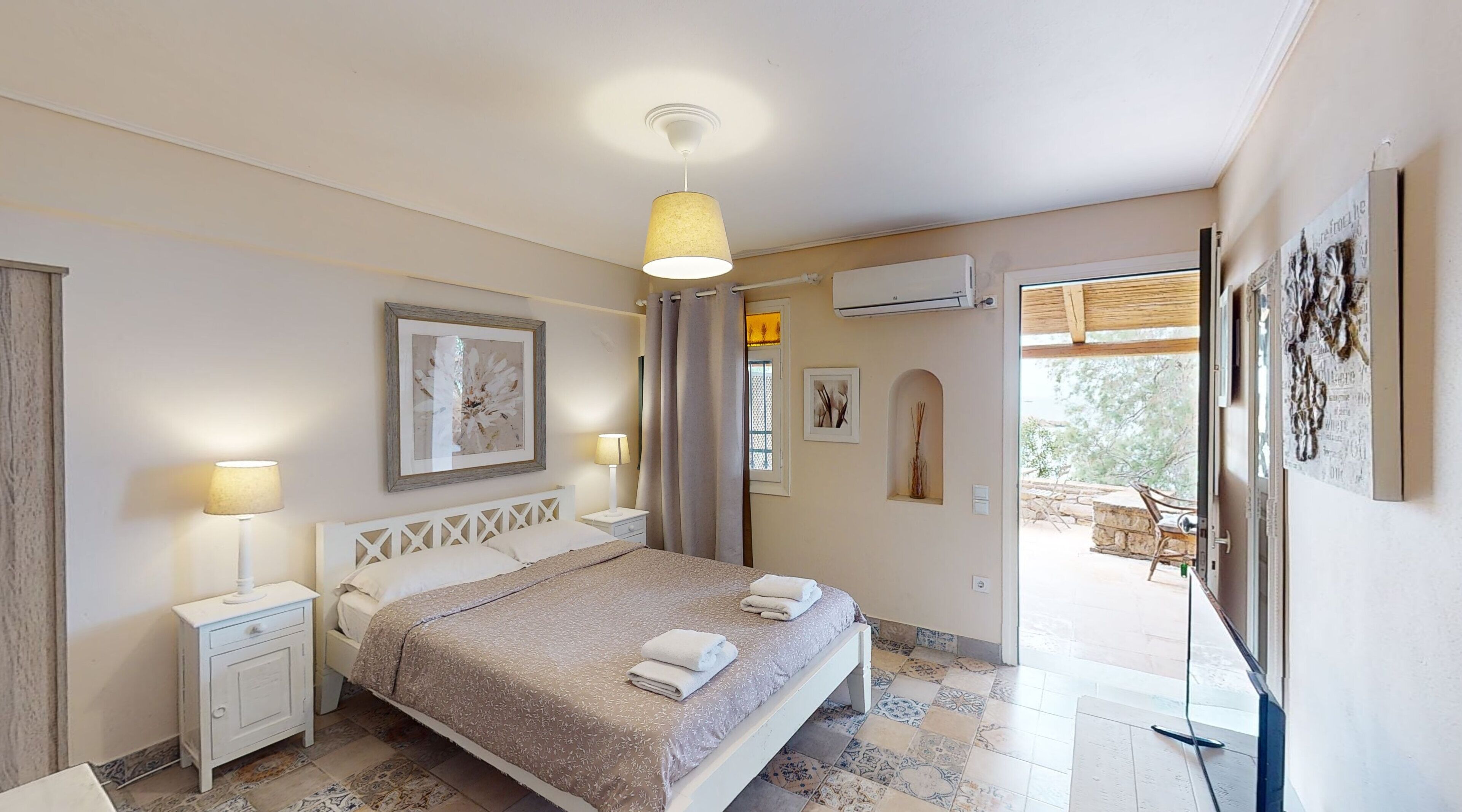 Un dormitorio con cama, mesitas de noche, lámpara colgante, equipo de aire acondicionado y vista al exterior.