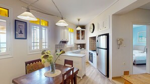 Eine kompakte Küche mit weißen Schränken, einem Edelstahlkühlschrank und einer Essecke mit Holztisch und Stühlen.