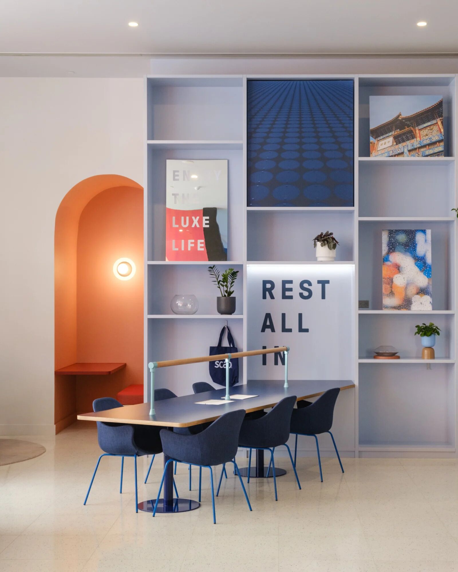 A modern dining area with a table, chairs, and a bookshelf with various items.