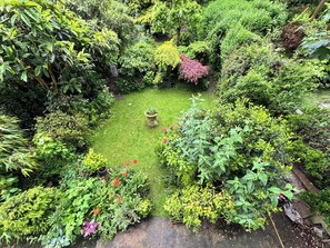 A lush garden with a variety of plants and a central decorative feature.