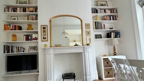 A living room with a fireplace, bookshelves, a television, and a decorative orange slice on the rug.