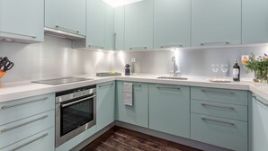 A modern kitchen with light blue cabinets, stainless steel appliances, and a wooden floor.