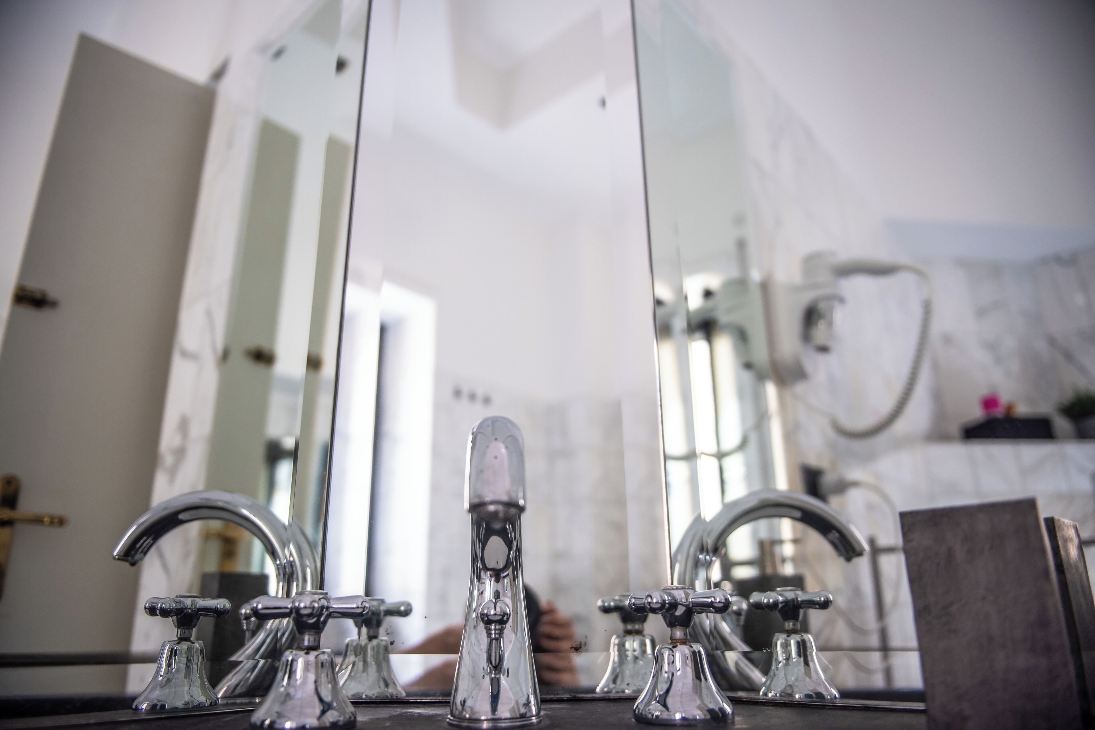 A bathroom with a modern sink, two faucets, and a large mirror reflecting the room.