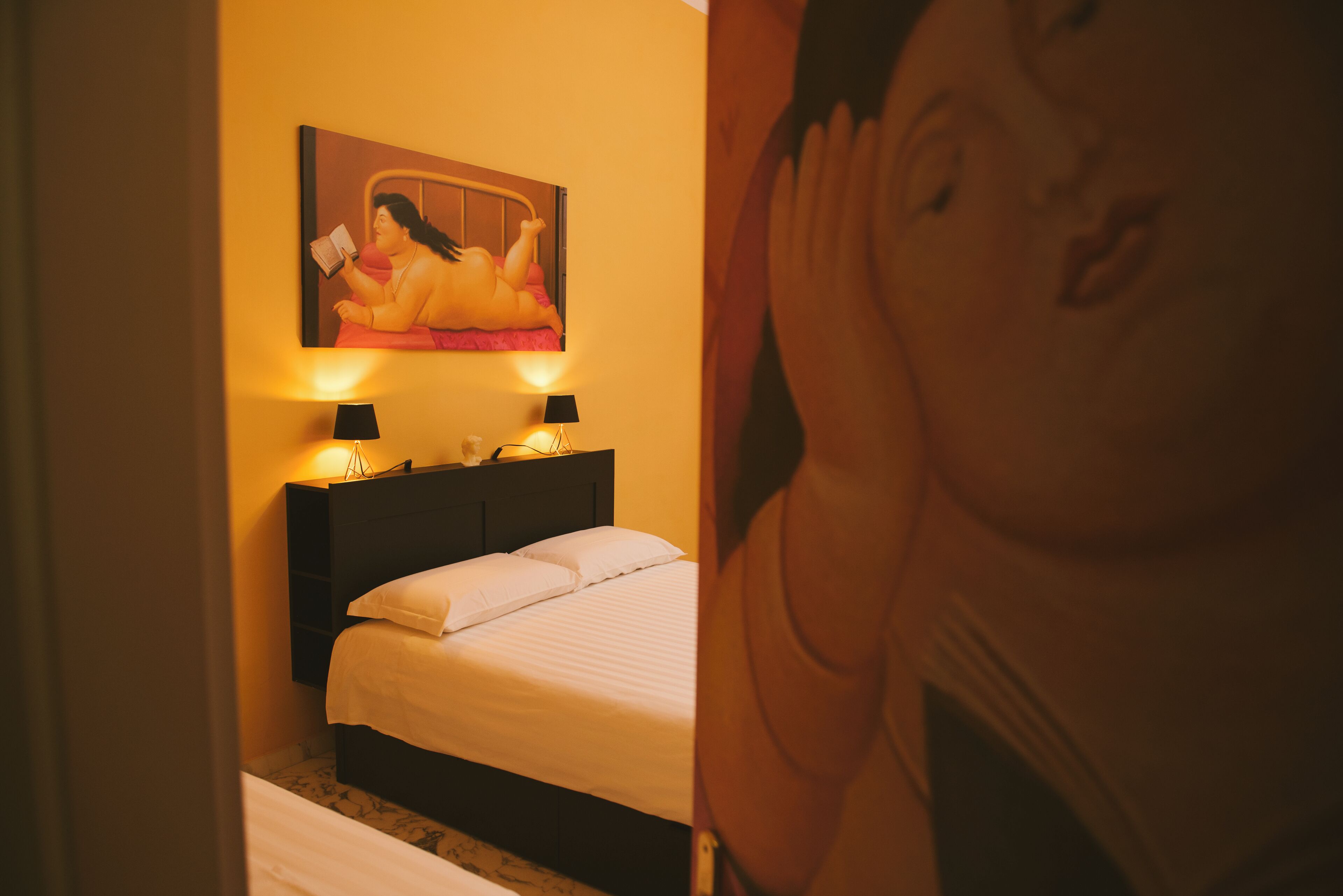 Un dormitorio con cama, dos lámparas de noche y un cuadro en la pared.