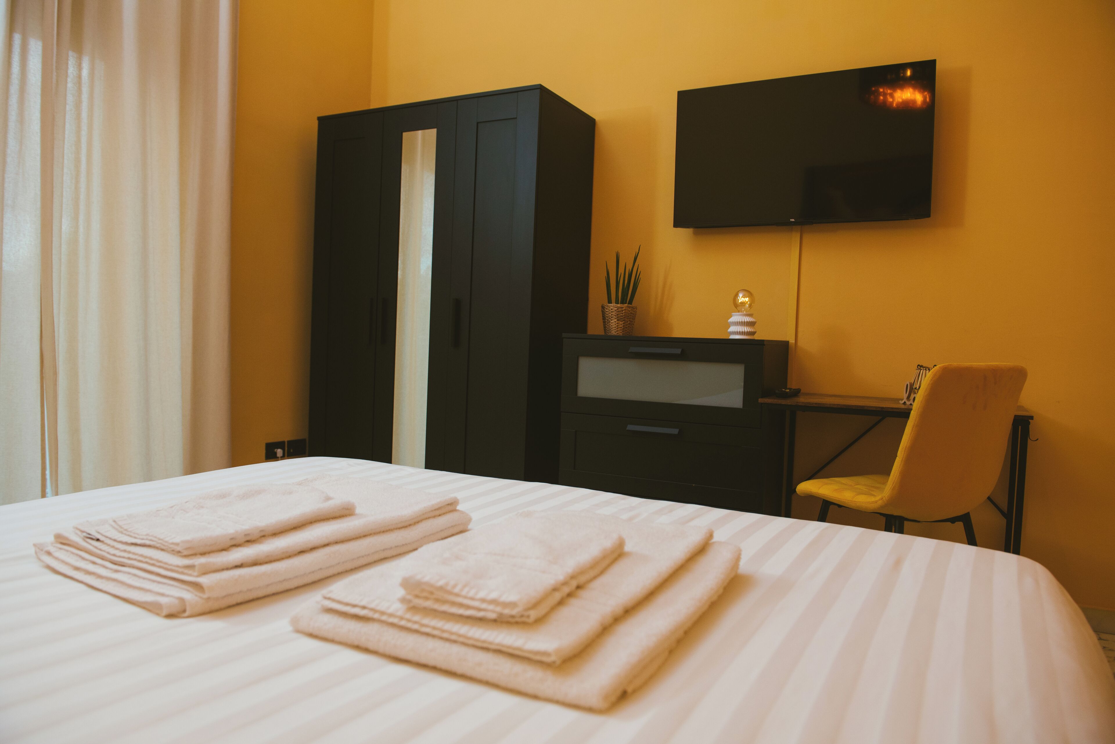 Een hotelkamer met een bed, een bureau, een stoel, een televisie en een kledingkast.