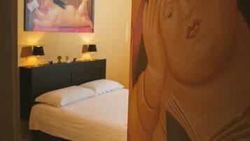 Ein Hotelzimmer mit Bett, Nachttischlampen, einem kleinen Tisch und einem großen Gemälde an der Wand.