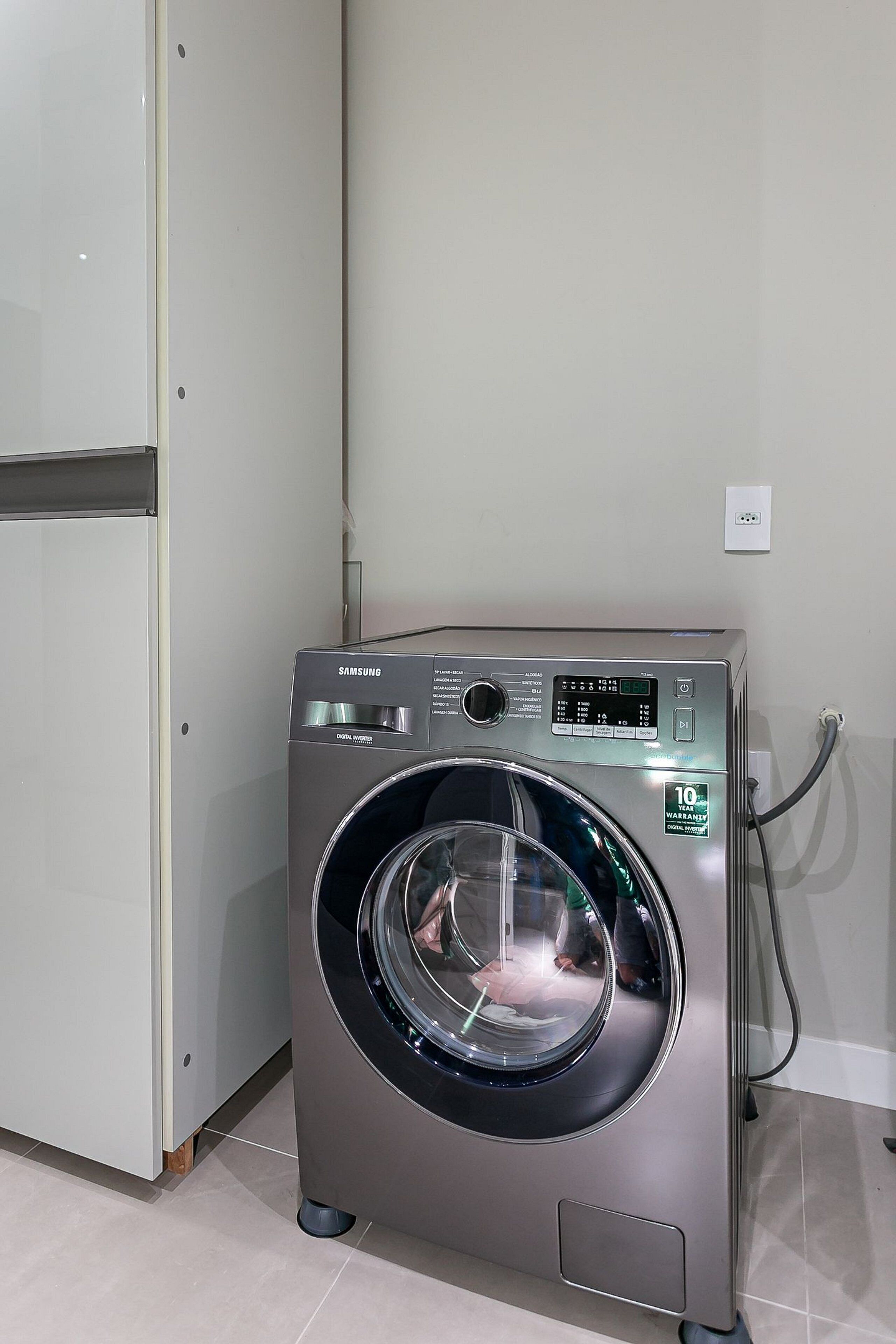 A Samsung digital washing machine in a room with a white door and tiled floor.