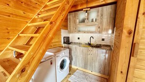 Cocina compacta con lavadora, armarios de madera y microondas integrado.