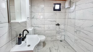 Un baño con lavamanos, inodoro y ducha blancos.