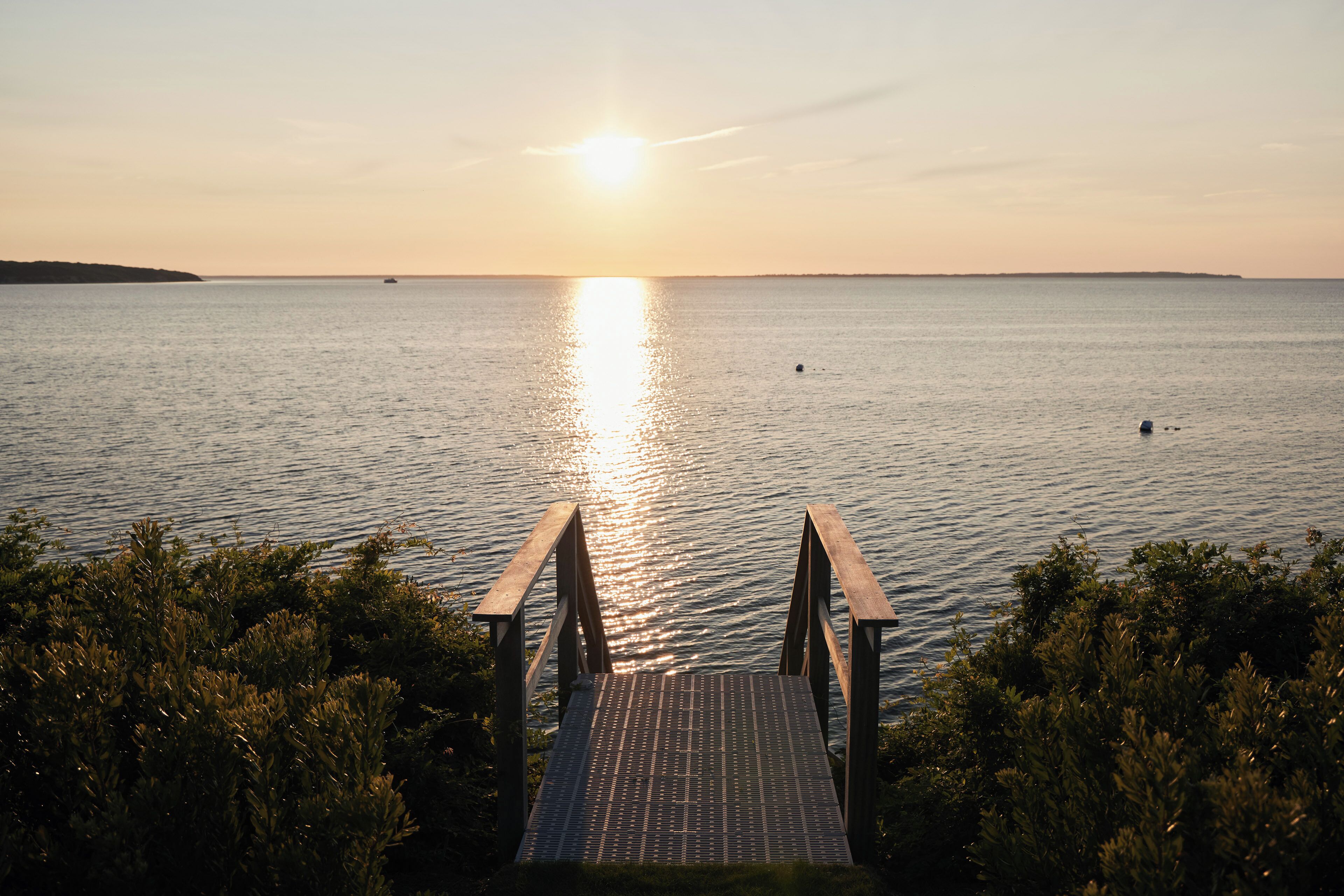 A wooden dock leading into calm waters with a sunset in the background.