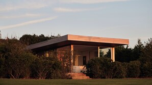 Une maison moderne avec un toit plat, de grandes fenêtres et une véranda couverte.
