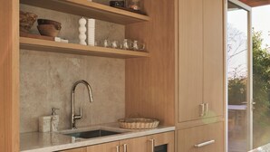 Une cuisine moderne avec des meubles en bois, un évier en acier inoxydable et une fenêtre donnant sur l’extérieur.