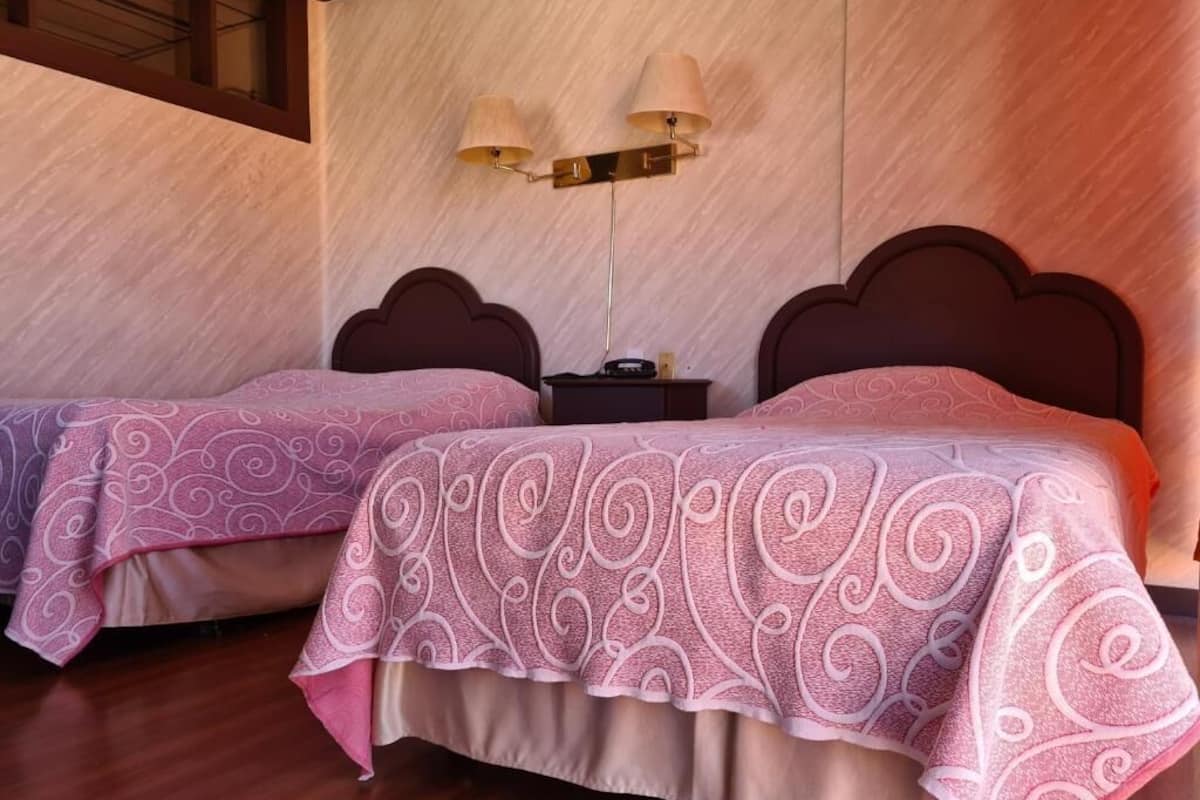 Duas camas com cabeceiras iguais e uma mesa de cabeceira no meio.