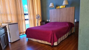 Una camera da letto con un letto, una scrivania, una ventola e una finestra con tende.