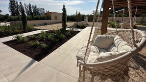 Una silla hamaca en un jardín con un edificio de piedra al fondo.