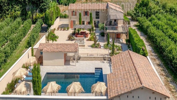 Una villa con piscina, mobiliario de exterior y jardín.