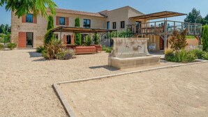 Una casa de dos pisos con un patio, un espacio de estar techado al aire libre y una piscina.