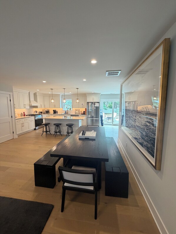 A modern kitchen with white cabinets, a central island, bar stools, and pendant lighting.