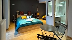 Un dormitorio moderno con cama, mesitas de noche, un escritorio pequeño y una silla.