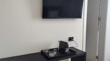A modern room with a black console table, a flat-screen TV mounted on the wall, and a coffee maker on the table.