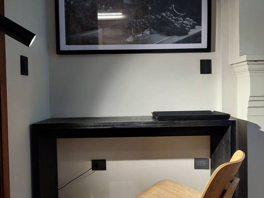 A modern office space with a desk, chair, and a framed picture on the wall.