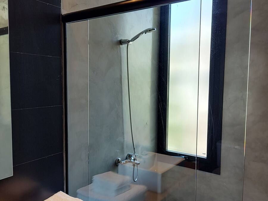 Un baño moderno con ducha acristalada, lavabo y ventana.