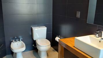 A modern bathroom with a bidet, toilet, and sink.