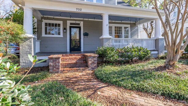 A two-story house with a porch, number 702, brick steps, and a well-maintained garden.