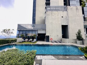 A modern building with a swimming pool, outdoor seating, and a view of the city skyline. - Spacious Duplex Oasis Icon City (Petaling Jaya)