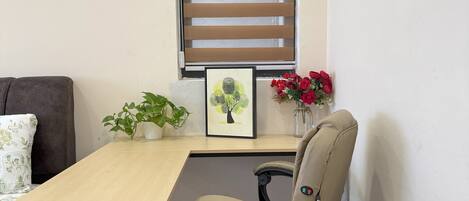 Un pequeño espacio de oficina con un escritorio, una silla y una ventana con persianas.
