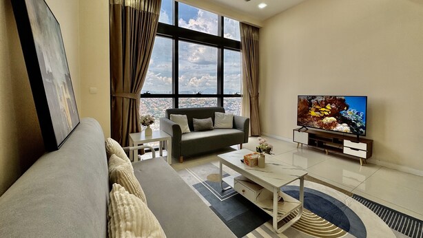 Una sala de estar moderna con sofá, mesa de centro, televisor y ventanas amplias que ofrecen vista a la ciudad.